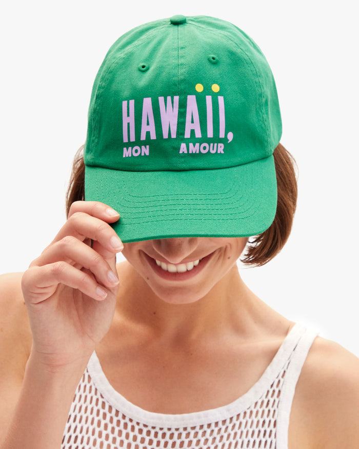 Model wearing the Hawaii Mon Amour Baseball Hat and holding the visor part of the hat down.