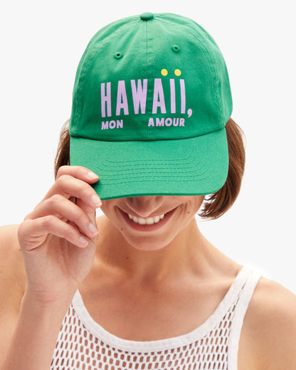 Model wearing the Hawaii Mon Amour Baseball Hat and holding the visor part of the hat down.
