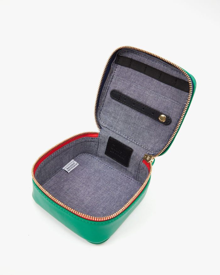 Inside of the Emerald Nappa Box A Bijoux. The inside is lined with chambray and has a leather strap to attach earrings and  brooches. and an elastic band that holds bracelets.